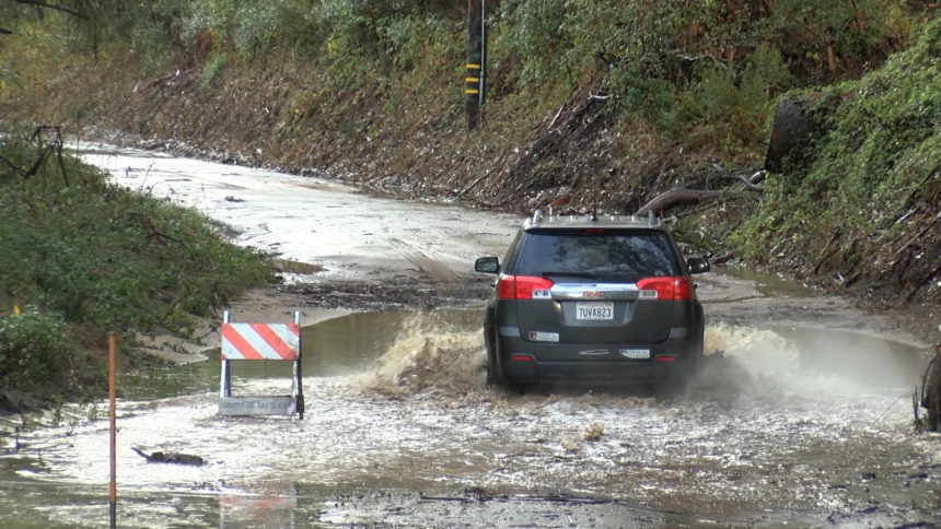 CAR DRIVES THROUGH FLOODED STREET