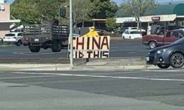 Hazmat-costumed person holding up "China Did This" sign in Salinas