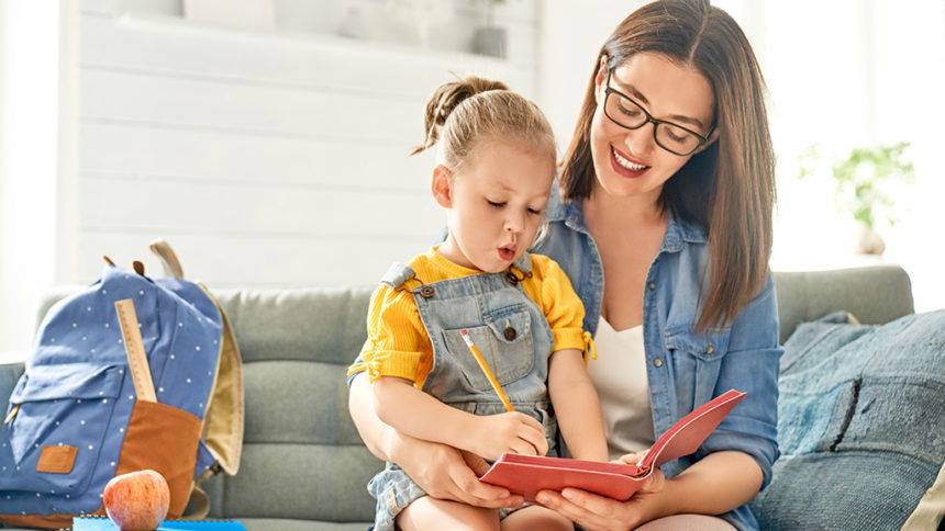 mother and her daughter are writing in notebook.