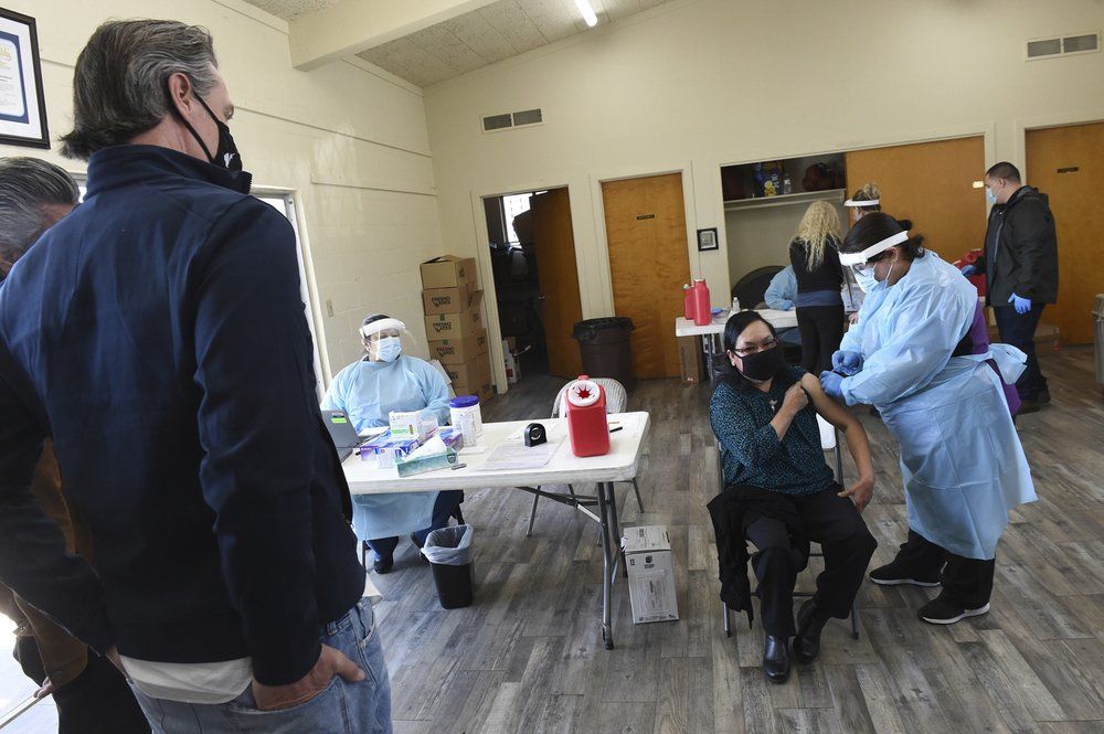 In this Friday, Feb. 26, 2021, file photo, California Gov. Gavin Newsom watches as a farmworker receive the Pfizer COVID-19 vaccine at a vaccination clinic for farmworkers at the Dr. Sharon Stanley-Rea Community Center in Fresno, Calif. California Gov. Gavin Newsom's administration says the massive new federal coronavirus relief bill will pump more than $150 billion into the state's economy. Nearly half of that money will go to Californians directly in the form of $1,400 stimulus checks and expanded unemployment benefits. Another $26 billion will go to the state government. 
