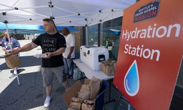 Carlos Ramos hands out bottles of water and sack luncheson Monday at a hydration station in front of the Union Gospel Mission in Seattle.