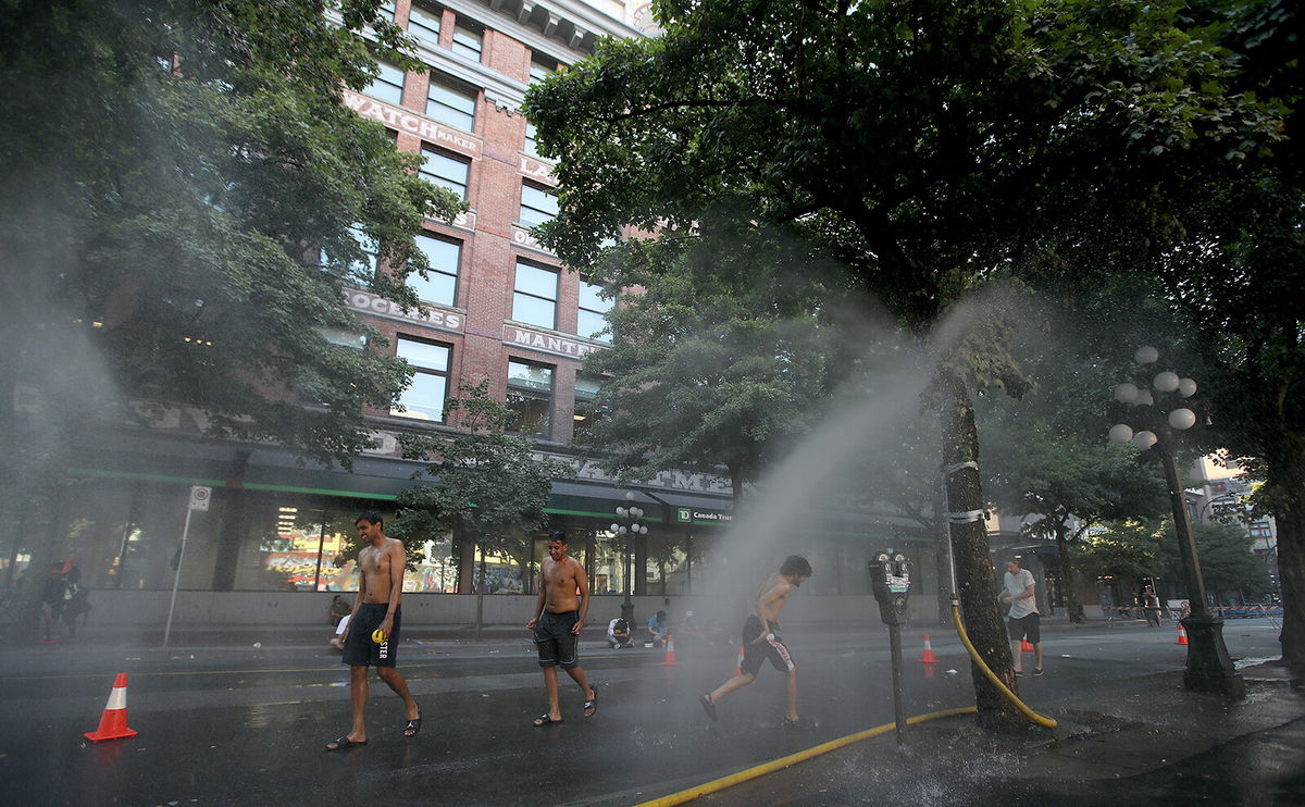 <i>Trevor Hagan/BloombergGetty Images</i><br/>A temporary misting station in Vancouver cools residents amid the extreme heat.