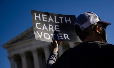 A supporter of the Affordable Care Act (ACA) stands in front of the Supreme Court of the United States in 2020.