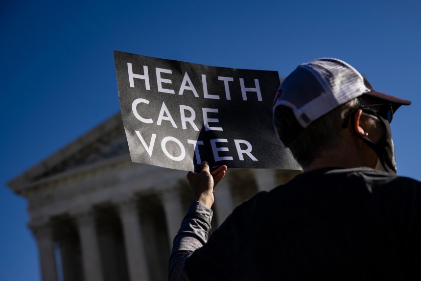 A supporter of the Affordable Care Act (ACA) stands in front of the Supreme Court of the United States in 2020.