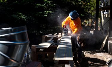 A contractor uses a saw to cut siding for a house under construction in Walnut Creek