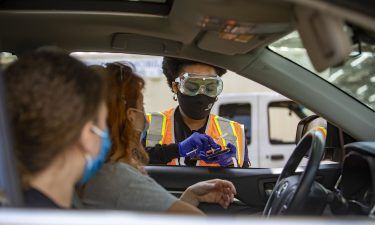 A healthcare worker speaks with a teenager before administering a dose of the Pfizer-BioNTech Covid-19 vaccine at a drive-through clinic at California State University