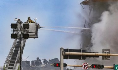 Firefighters battle a blaze as rescue workers search debris at the 12-story oceanfront condo