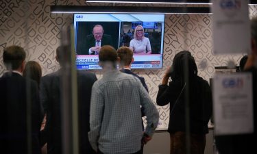 Staff in the green room watch a television screen showing Andrew Neil and Michelle Dewberry broadcast from a studio