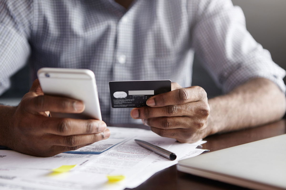 <i>Shutterstock</i><br/>A man uses his phone and credit card to pay bills. Companies are beginning to give employees access to their paychecks before pay day.