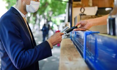 A man pays at a coffee stall. The US economy is showing signs of recovery. That could also mean spending more money on activities that people may not have done in a while -- like going to the movies