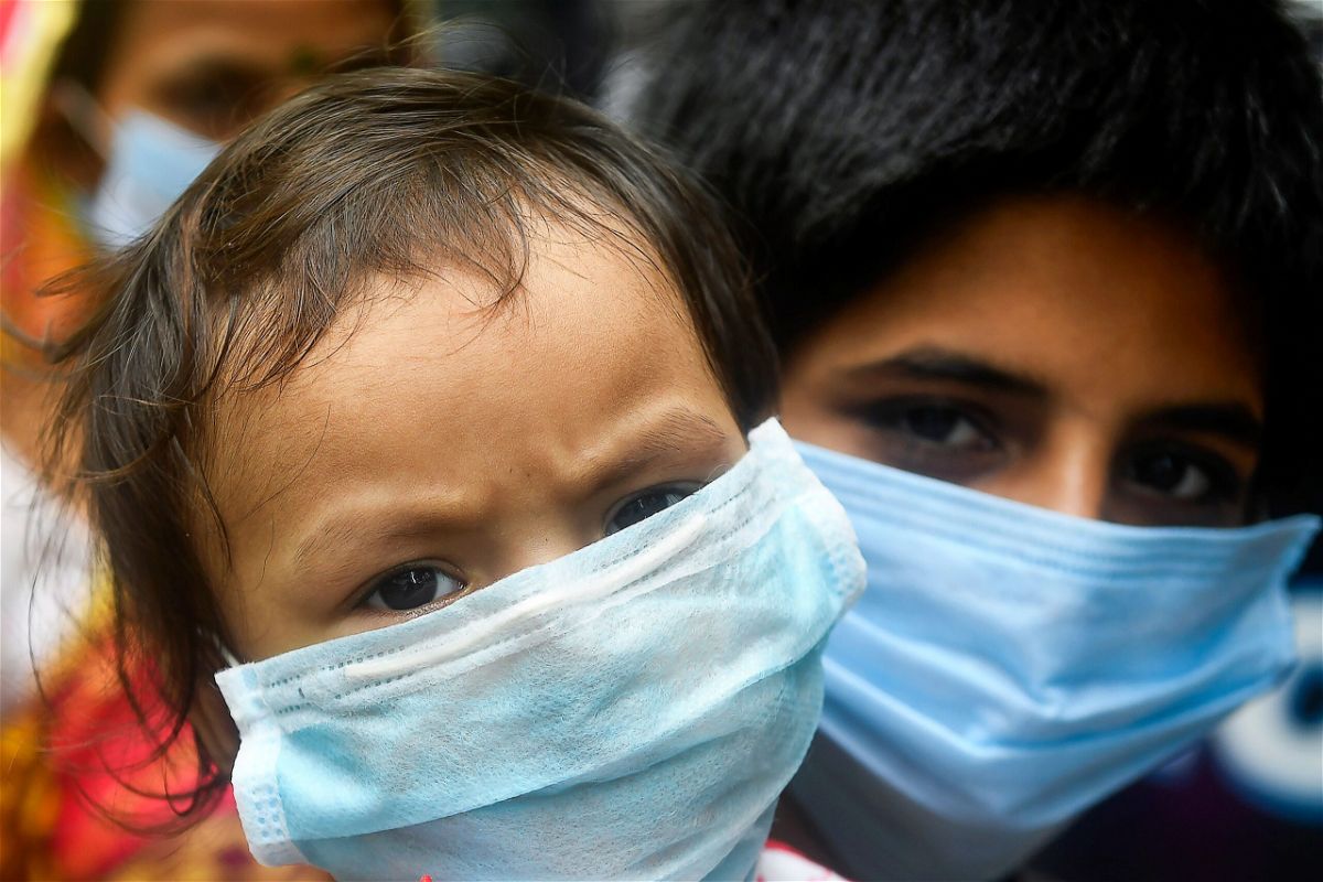 <i>DIBYANGSHU SARKAR/AFP/AFP via Getty Images</i><br/>Children wear facemasks and wait in a queue with others to take swab samples to test for the Covid-19 coronavirus