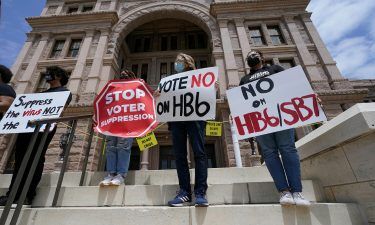 People opposed to Texas voter bills HB6 and SB7 hold signs during a news conference hosted by Texas Rising Action on the steps of the State Capitol in Austin