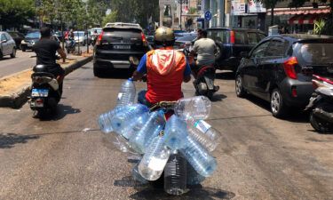A man rides his scooter with empty water bottles to fill them with gasoline