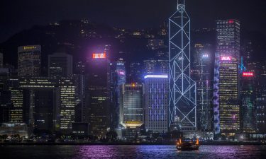 A boat sails on along Victoria Harbor past the People's Liberation Army (PLA) Hong Kong Garrison building