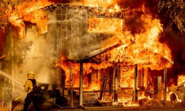 A firefighter sprays water while trying to stop the Sugar Fire