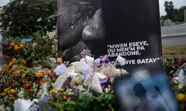 A man is reflected on a cellphone at a memorial outside the Presidential Palace in memory of slain President Jovenel Moise