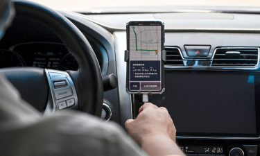 A driver uses the Didi Chuxing ride-hailing app on his smartphone while driving along the street in Beijing on July 2.