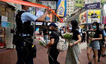 People hold flowers to mourn the death of the assailant.