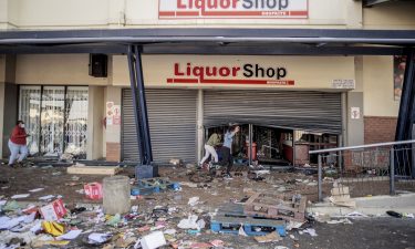 Rioters run from police officers after looting a liquor shop at the Jabulani Mall in the Soweto district of Johannesburg on July 12.