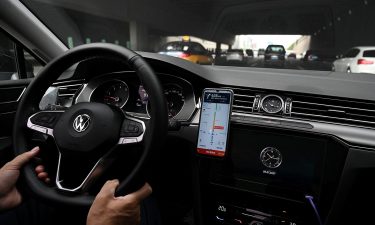 A driver uses the map on the Didi Chuxing ride-hailing app on his smartphone while driving on a street in Beijing.