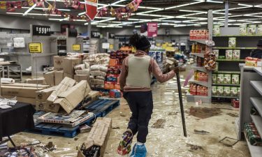 A police officer inspects the damage at a looted mall in Vosloorus