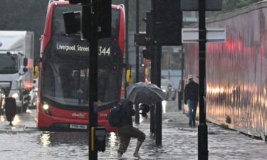 A pedestrian crosses through deep water on a flooded road in London on July 25. Climate and infrastructure experts have been warning for years that London
