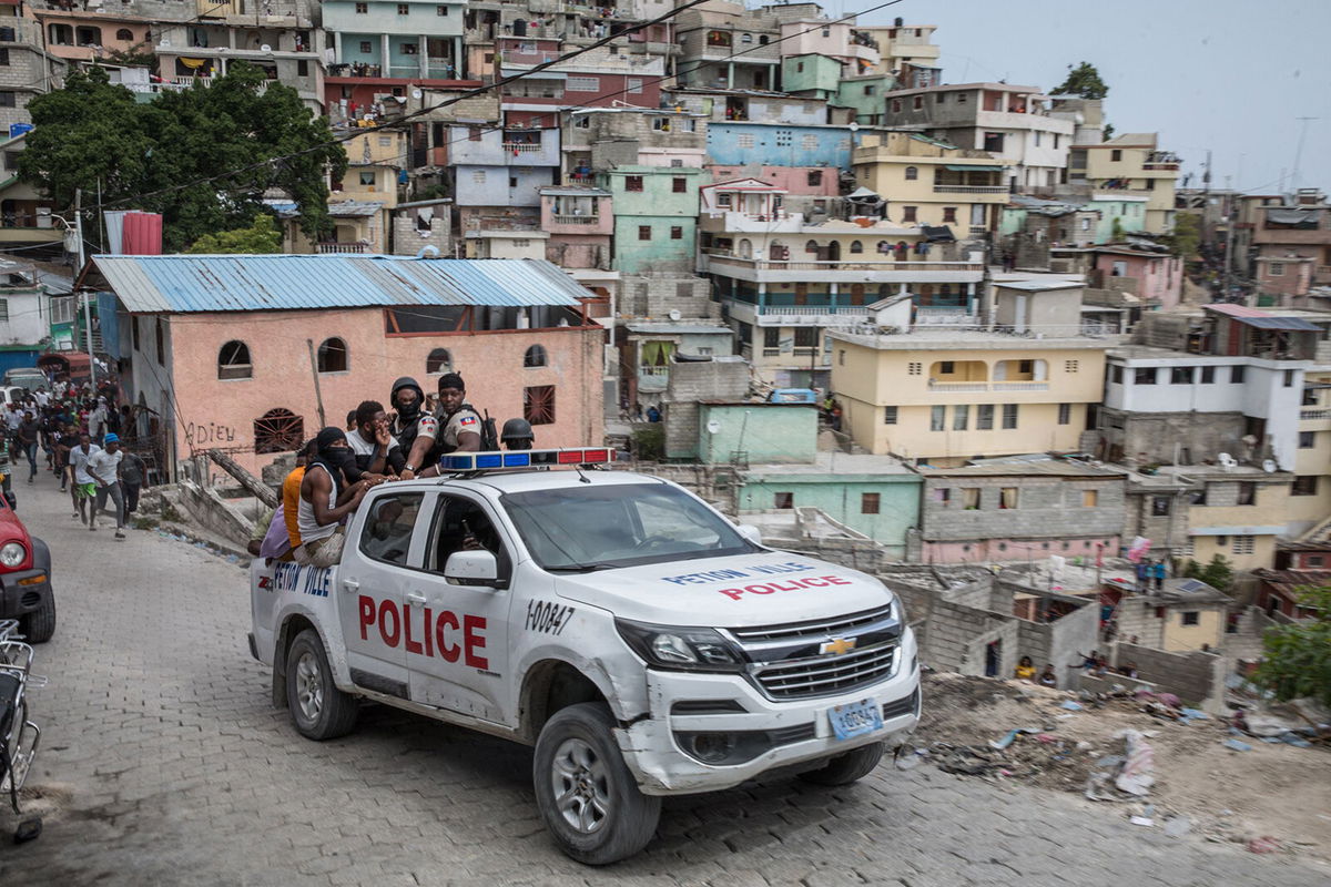 <i>Valerie Baeriswyl/AFP/Getty Images</i><br/>A police car filled with civilians and policemen drives up the Jalousie township where men accused of being involved in the assassination of President Jovenel Moise