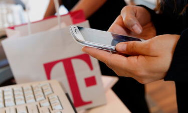 An employee sets up a new Samsung  Electronics Co. Galaxy 3 smartphone for a customer at a T-Mobile US Inc. retail store in Torrance