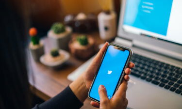 A woman holds an iPhone with Twitter on the screen.