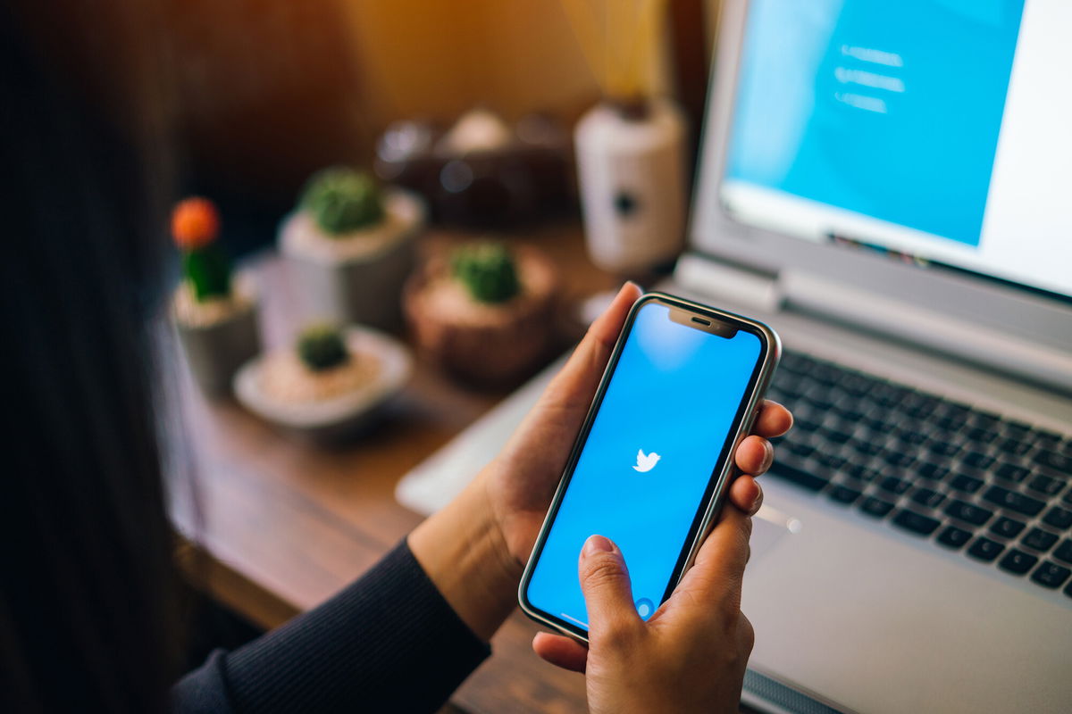 <i>Shutterstock</i><br/>A woman holds an iPhone with Twitter on the screen.