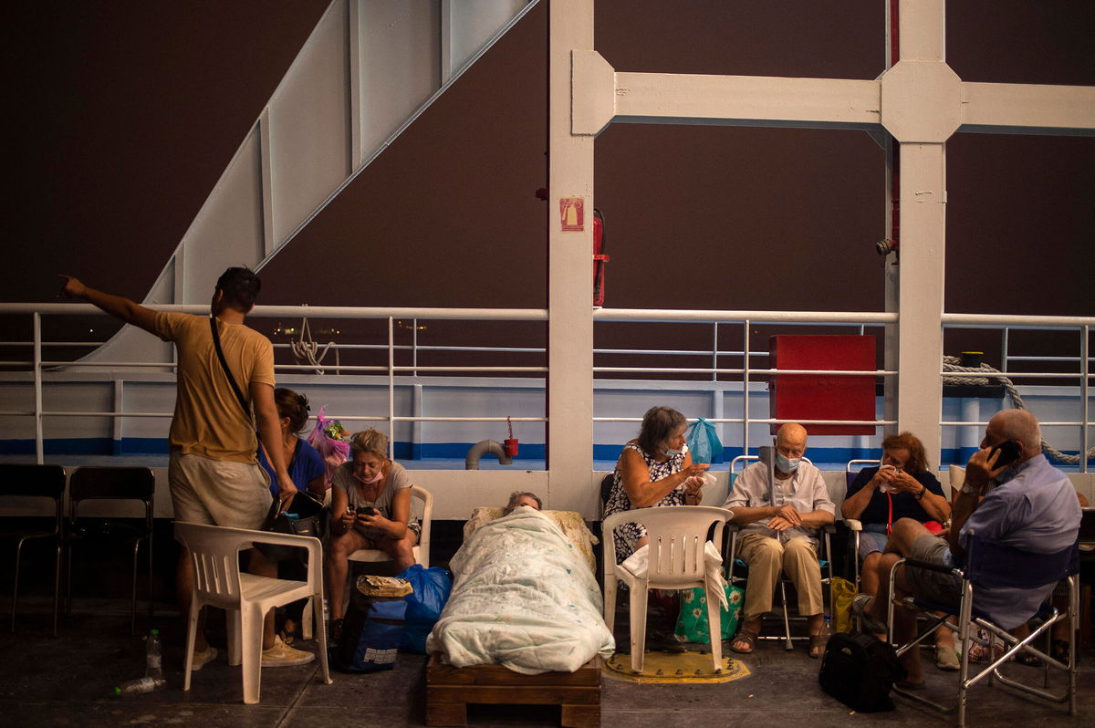 <i>ANGELOS TZORTZINIS/AFP/AFP via Getty Images</i><br/>Elderly people are seen on chairs and makeshift bed onboard a ferry at the port of the village of Pefki