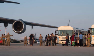 A group of Afghan evacuees depart a C-17 Globemaster III aircraft at Ramstein Air Base