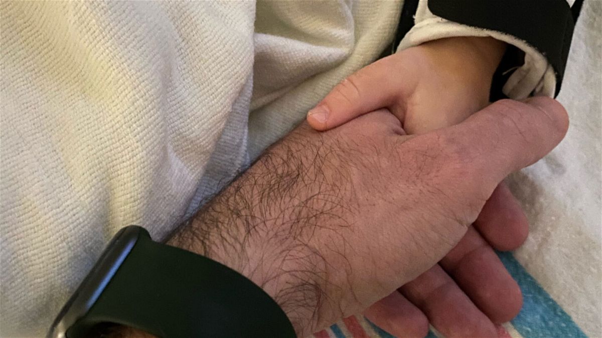 <i>Courtesy Ben Tinker</i><br/>Ben Tinker holds his 16-month-old son's hand while he sleeps in the pediatric intensive care unit.