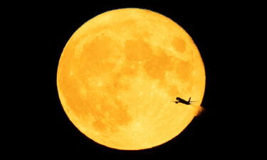 An aircraft passes in front of a Sturgeon moon (true blue moon) after takeoff from Minneapolis-St. Paul International Airport on August 3