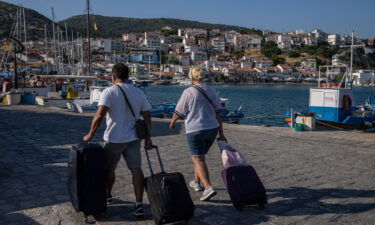 People sit on a beach in Kokkari in front of a tavern on the eastern Aegean island of Samos