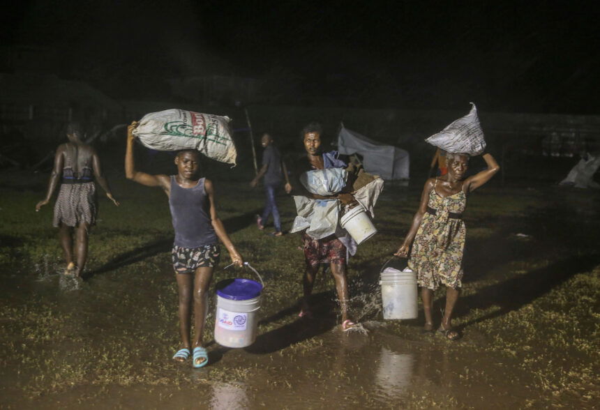 People affected by the earthquake walk under the rain of Tropical Depression Grace at a refugee camp in Les Cayes