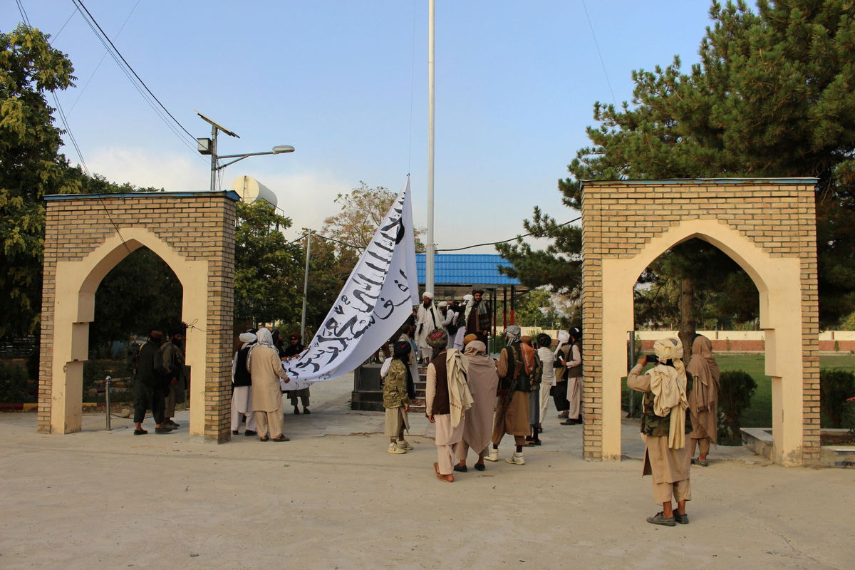 <i>Gulabuddin Amiri/AP</i><br/>Taliban fighters raise their flag at the provincial governor's house in Ghazni