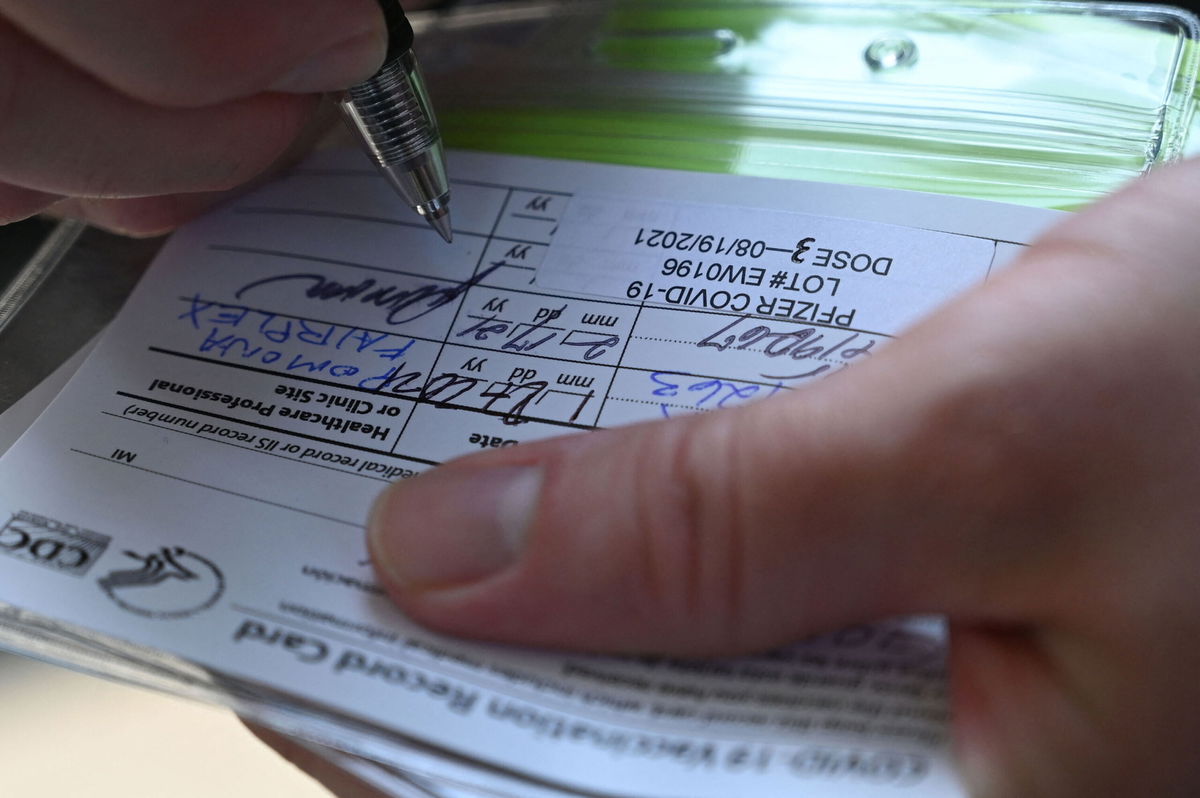 <i>Robyn Beck/AFP/Getty Images</i><br/>A nurse marks a coronavirus vaccination card with a third booster dose of Pfizer