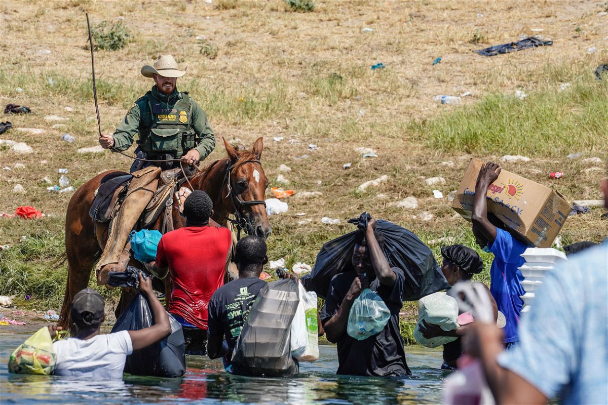 <i>Paul Ratje/AFP/Getty Images</i><br/>A United States Border Patrol agent on horseback uses the reins as he tries to stop Haitian migrants from entering an encampment. The DHS has since temporarily suspended the use of horse patrol.