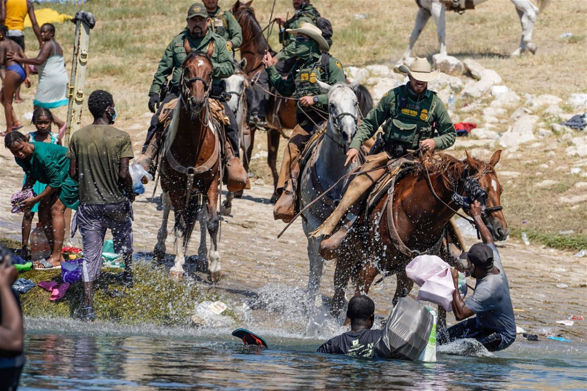 <i>Paul Ratje/AFP/Getty Images</i><br/>US Border Patrol agents on horseback try to stop Haitian migrants on Sunday from entering an encampment on the banks of the Rio Grande near the Acuna Del Rio International Bridge in Del Rio