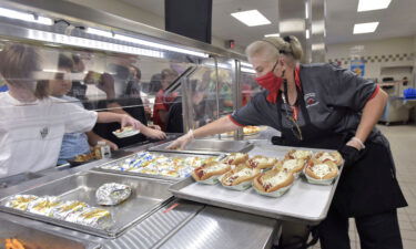 Laura Vance puts out some food items on the lunch line in the Sims Middle School cafeteria in Pace