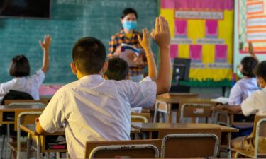 Students and their teacher wear protective face masks in their elementary school.