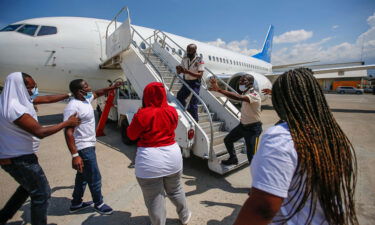 Police officers try to block a deportee from boarding the same plane he and others were deported in.