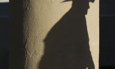 A shadow of a man wearing a cowboy hat falls on a pillar as he enters the polling place at Wickenburg Community Center on February 28