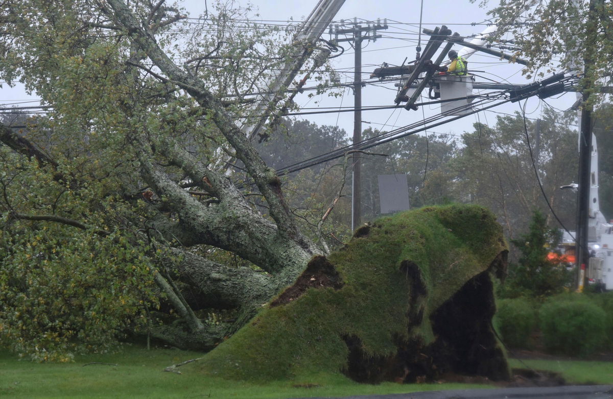 <i>Steve Heaslip/Cape Cod Times/AP</i><br/>Crews are working to restore power to hundreds of thousands in New England. An uprooted large tree brought down power lines in Sandwich