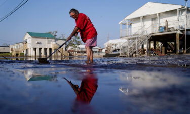 Cindy Rojas cleans mud and floodwater from her driveway in Lafitte