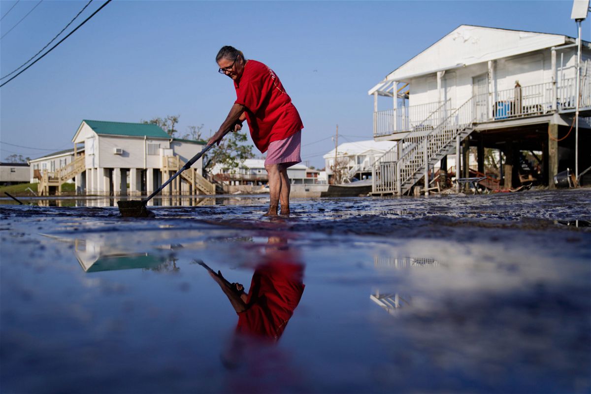 <i>John Locher/AP</i><br/>Cindy Rojas cleans mud and floodwater from her driveway in Lafitte