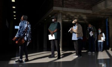People wait in line with their paperwork to receive their coronavirus booster vaccination during a Pfizer-BioNTech vaccination clinic in Southfield