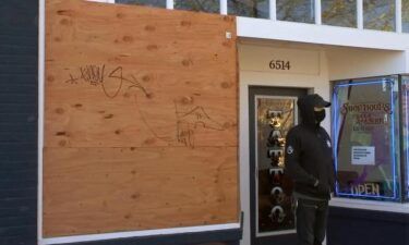 A board covers a window broken during vandalism at a tatoo shop in Portland
