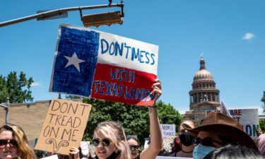 Protesters hold up signs as they march down Congress Ave at a protest outside the Texas state capitol on May 29